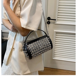 Detailed view of black cylindrical bag featuring silver rhinestones and chain strap
