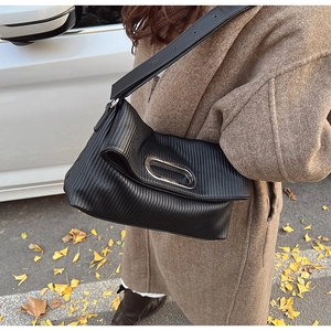 Detail of black pleated shoulder bag with silver metal ring and adjustable strap
