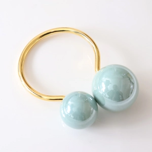 Detail view of U-shaped golden napkin ring with elegant light green faux pearl accents