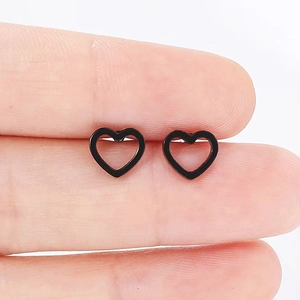 Minimalist black hollow heart stud earrings in stainless steel shown for scale