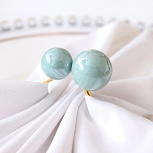 Macro shot of mint green dual pearls on golden ring set on white silk fabric