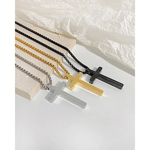 Detailed view of polished black, gold, and silver stainless steel cross necklaces on stone