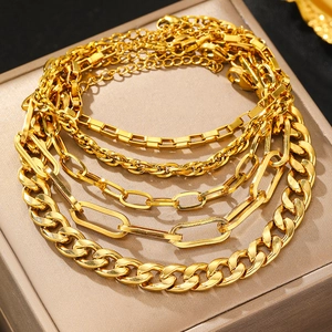 Gold multi-layered bracelet set featuring chunky curb and paperclip chains on jewelry box