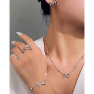 Close-up of bow-knot jewelry set including necklace, bracelet, ring and earrings on model
