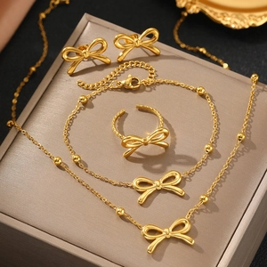 4-piece golden bow jewelry set with necklace, bracelet, ring, and earrings on gift box
