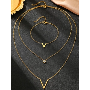 Détail de l'ensemble collier et bracelet en V doré avec zircon sur tissu en soie