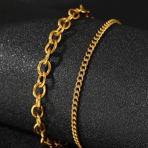 Macro view of gold curb and oval link chains with polished finish on black texture