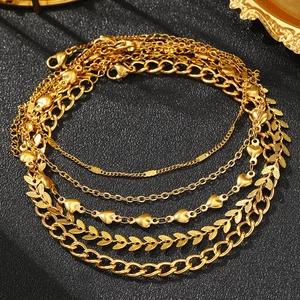 Dettaglio del set di cinque cavigliere dorate boho con ciondoli a cuore e maglia cubana