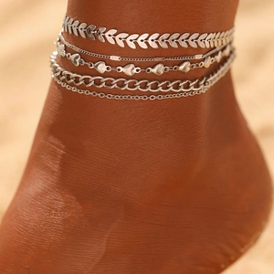Dettaglio del set di quattro cavigliere boho argentate con motivi cubani e foglie