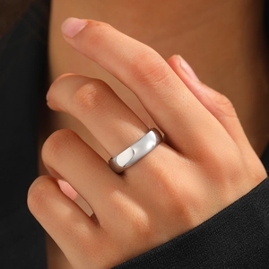 Polished silver stainless steel wide ring shown on a model against dark background