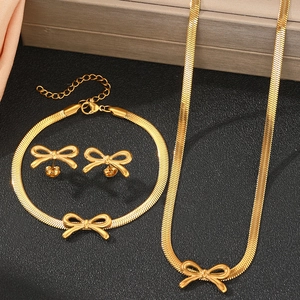 Golden bow jewelry set with necklace and bracelet on an elegant black tray background
