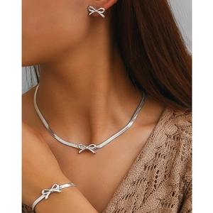 Close-up of elegant silver bow jewelry set including necklace, bracelet and earrings