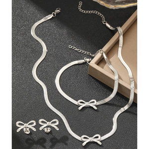 Minimalist silver bow jewelry set with necklace, bracelet and earrings on a display tray
