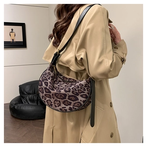 Leopard print crescent bag detail with leather strap on a model wearing a khaki coat