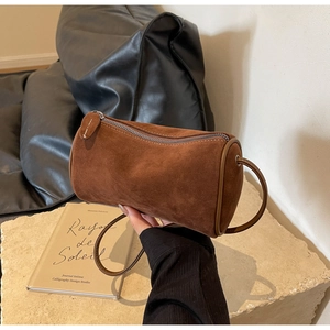 Detail of brown suede cylinder bag featuring high-quality silver zipper and leather edging