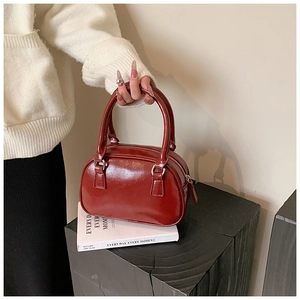 Detail of red patent leather bowling bag with silver hardware held by a model