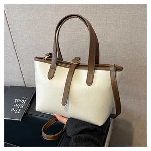 Detail of lychee pattern faux leather tote bag with brown contrast straps and handles