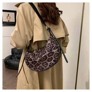 Detail view of leopard print half-moon crossbody bag with slim black leather shoulder strap