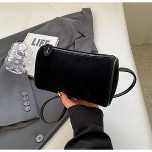 Close-up of black matte suede cylinder bag with zipper and white contrast stitching detail