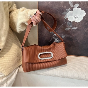 Detail of brown pleated shoulder bag with oval silver buckle and wide strap