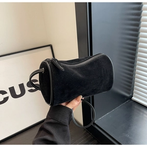 Close-up of black suede Boston bag with detailed white stitching on the curved handle