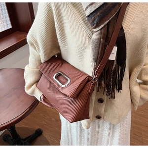 Detailed view of brown pleated texture bag with silver metallic clasp and leather strap