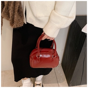 Detail showing red glossy patent leather bowling bag with silver metallic hardware