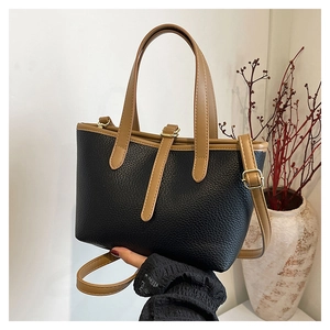 Detail of black lychee grain leather tote bag with brown handles and adjustable strap