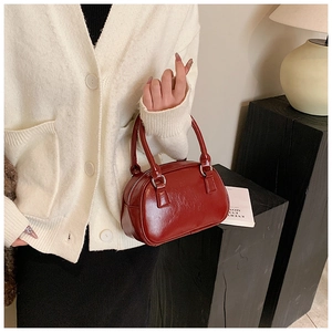 Detail of burgundy glossy leather handbag with double handles shown in a lifestyle setting