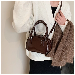 Detail of glossy brown patent leather bowling bag with dual handles and shoulder strap