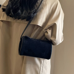Minimalist black matte Boston cylinder crossbody bag styled with a beige trench coat