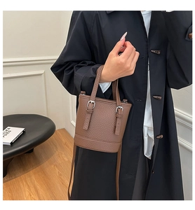 Détail du sac seau en cuir marron grainé avec boucles argentées et poignée ronde