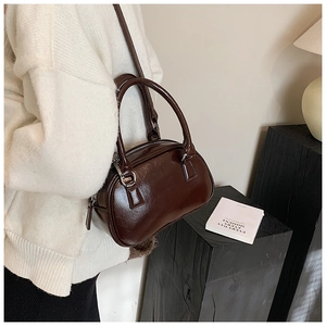 Detail of glossy brown leather bowling bag with vintage zipper and elegant handle