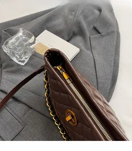 Close-up of brown quilted leather texture and smooth gold zipper on underarm bag
