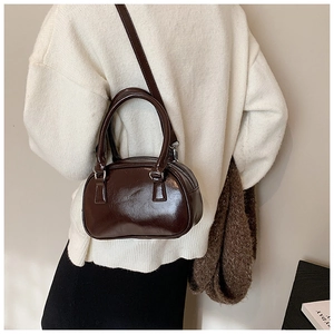 Detail of dark brown glossy patent leather Boston bag with silver hardware and shoulder strap