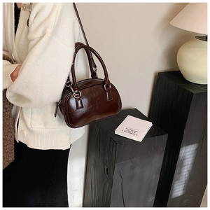 Detail of a dark brown vintage bowling bag with glossy faux leather and silver buckles