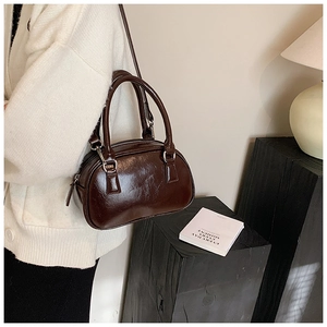 Detail of glossy deep brown bowling bag in polished faux leather with twin handles