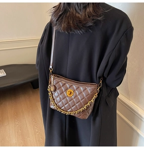 Detail of dark brown quilted shoulder bag with gold metal clasp and chain strap on model