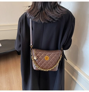 Detail of coffee quilted crossbody bag with golden turn-lock and chain strap
