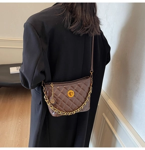 Detail view of brown quilted faux leather shoulder bag with gold chain and round buckle