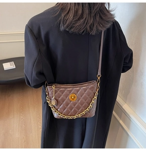 Detail of a dark brown quilted shoulder bag with gold hardware on a model back