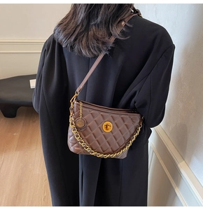 Detail of dark brown quilted leather shoulder bag with gold chain and round metal lock