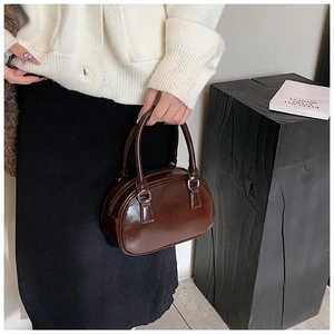 Detail of dark brown patent leather bowling bag with shiny finish and silver buckles