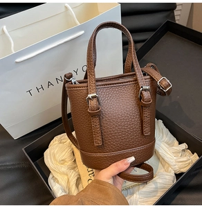 Vue détaillée d'un sac seau marron à motif litchi avec boucles décoratives