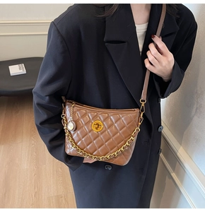Close-up of brown quilted leather hobo bag with gold chain and turn-lock on a model