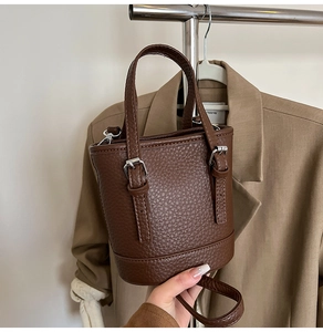 Détail du mini sac seau en cuir grainé marron foncé avec boucle argentée et poignée