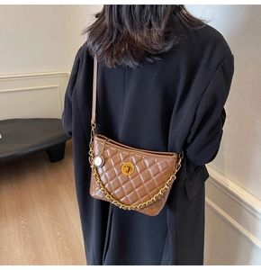 Detailed back view of a brown quilted bucket bag with gold chain strap on a model