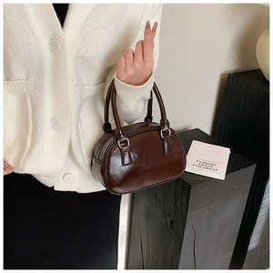 Detail of dark brown patent leather handbag with glossy mirror finish and silver buckles