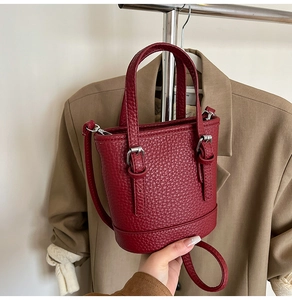Détail du sac seau bordeaux en cuir grainé avec boucles et finitions en métal argenté