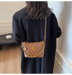 Detail of a brown quilted leather shoulder bag with gold chain and twist-lock buckle